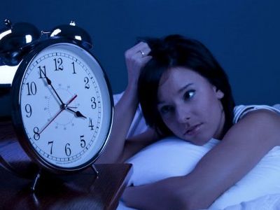 woman in bed with clock beside her