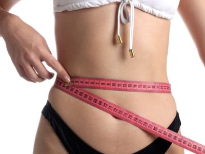 woman measuring waist using pink tape