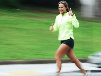woman in green jogging and giving a thumbs up